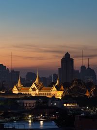 Illuminated city at waterfront during sunset