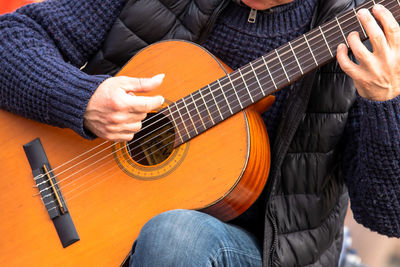 Midsection of man playing guitar