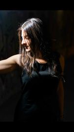 Young woman looking away while standing in darkroom