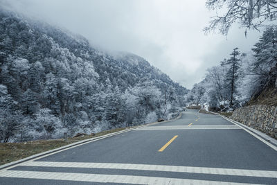 Road amidst snowcapped mountains against sky