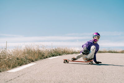 Downhill skateboarder on alpine road with blue sky as background