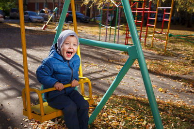 Happy boy sitting on slide at playground