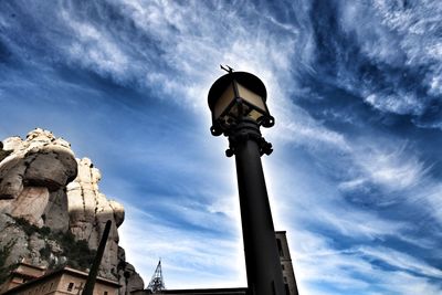 Low angle view of street light by building against sky