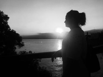 Side view of silhouette woman looking at sea against sky