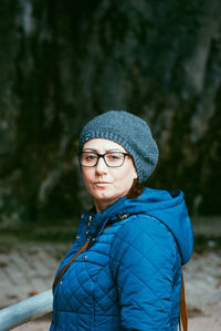 Portrait of woman wearing warm clothing while standing against rock formation