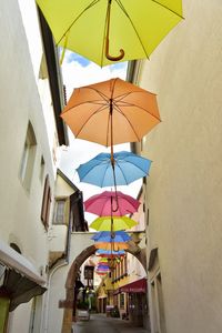 Low angle view of umbrellas hanging against buildings in city