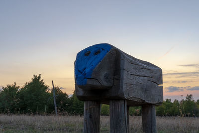 Wooden post on field against clear sky during sunset