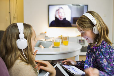 Happy sisters listening music on digital tablets in living room