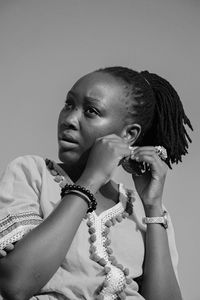Portrait of young woman looking away against gray background