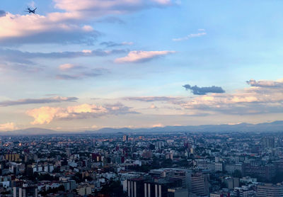 High angle view of city at sunset while a plane is landing