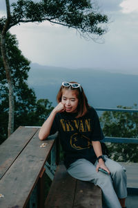 Portrait of woman sitting against trees