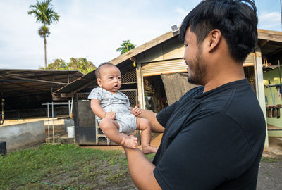 Father and son holding baby while standing outdoors