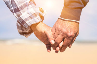 Close-up of man holding hands against sky