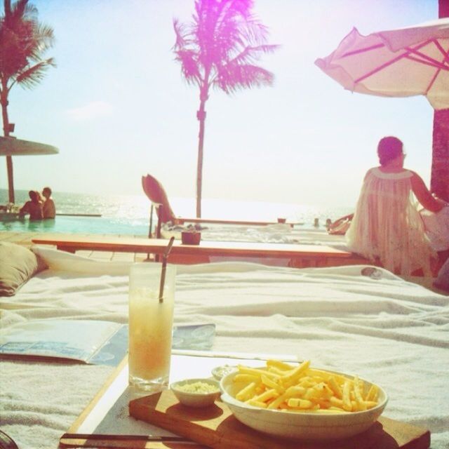 sea, table, water, horizon over water, beach, food and drink, drink, freshness, restaurant, parasol, incidental people, chair, vacations, sky, leisure activity, day, beach umbrella, drinking glass, clear sky