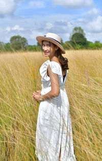 Portrait of woman in hat standing on field