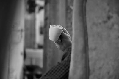 Close-up of hand holding paper against wall