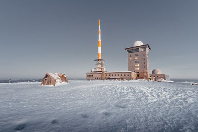 Buildings at frozen sea against sky