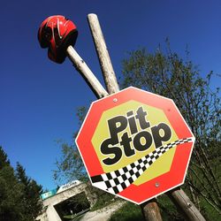 Low angle view of road sign against clear blue sky