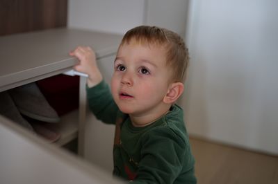 Portrait of cute little boy looking for his shoes in locker