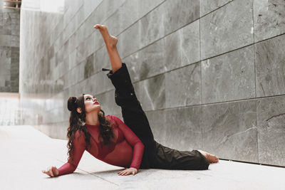 Full length of woman dancing on floor against wall