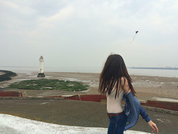 Rear view of woman looking at sea shore against sky