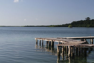 Wooden posts in lake against clear sky