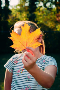 Midsection of woman holding maple leaves during autumn