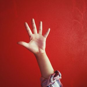 Close-up of cropped hand against red background