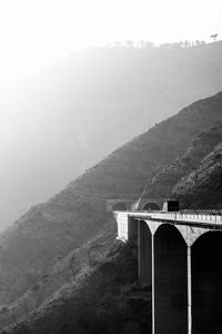 Arch bridge over mountains against sky