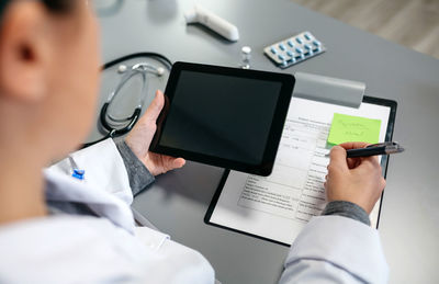 Midsection of man holding smart phone on table