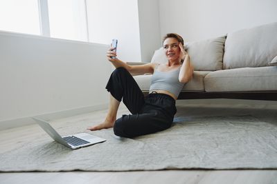 Young woman using mobile phone while sitting on sofa at home