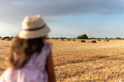 Rear view of woman standing on field against sky