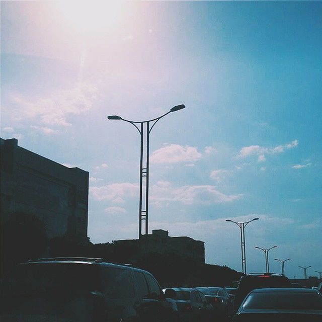 street light, sky, building exterior, car, built structure, architecture, silhouette, transportation, low angle view, land vehicle, mode of transport, cloud - sky, lighting equipment, street, sunlight, cloud, city, outdoors, no people, sun