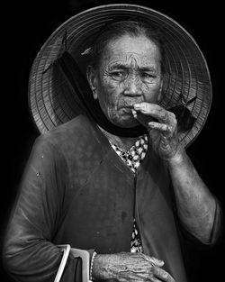 Portrait of woman wearing hat against black background