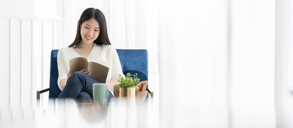 Young woman looking away while sitting on book