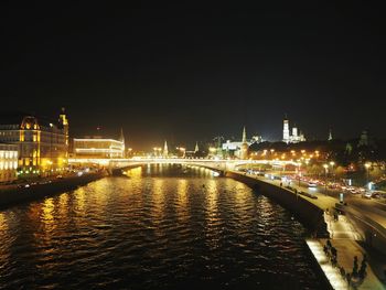 Illuminated bridge over river against sky at night