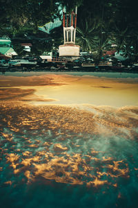 Digital composite image of illuminated trees and sea against sky