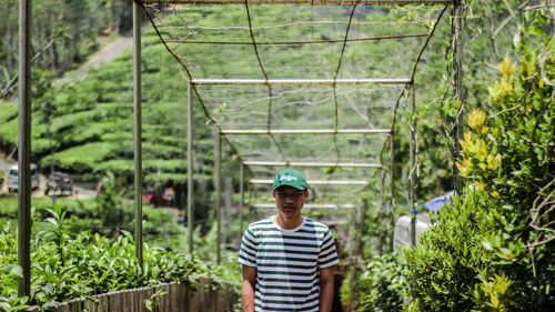 Portrait of young man standing against plants