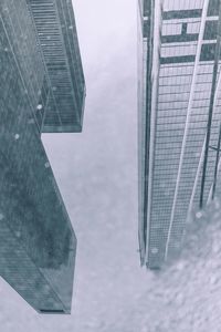 Reflection of buildings in puddle against sky