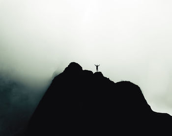 Silhouette of rock on mountain against sky