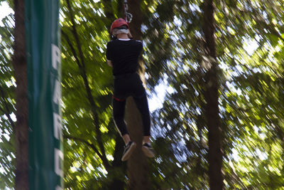 Low angle view of woman standing by tree