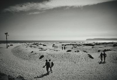 People walking at beach against sky