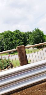 Plants and railing by trees against sky