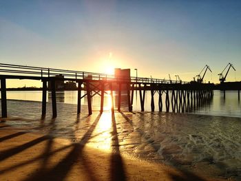 Pier over sea against sky during sunset