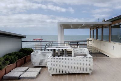 Chairs and table by sea against sky