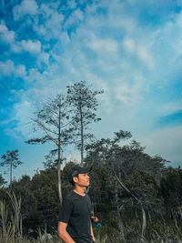 Man standing by tree against sky