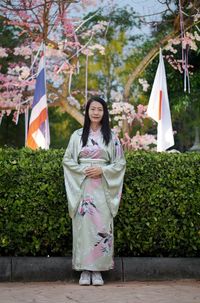 Woman holding flag while standing against plants