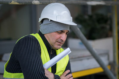 Engineer in reflective clothing with arms crossed standing at construction site