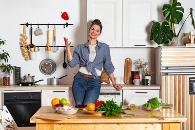 Young and beautiful housewife woman cooking in a white kitchen