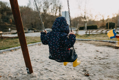 Rear view of girl sitting on swing